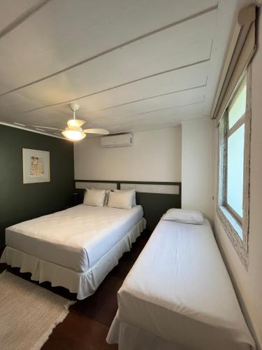 two beds in a room with green walls at Hotel Fita Azul in Ilhabela