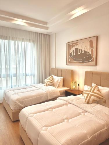 a hotel room with two beds and a window at The Apparte Salalah in Ţāqah