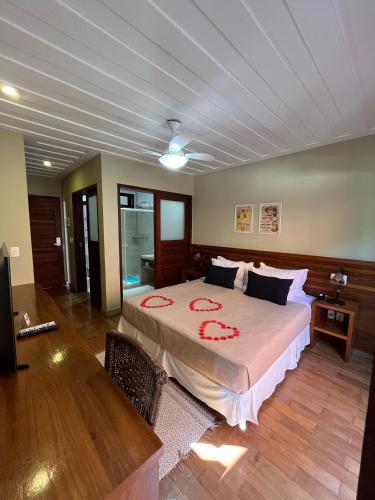 a bedroom with a large bed with red flowers on it at Hotel Fita Azul in Ilhabela