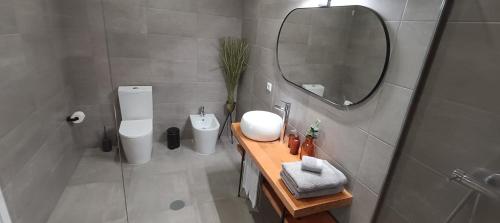 Un baño con lavabo, espejo e inodoro. en JM Stay, en Aveiro