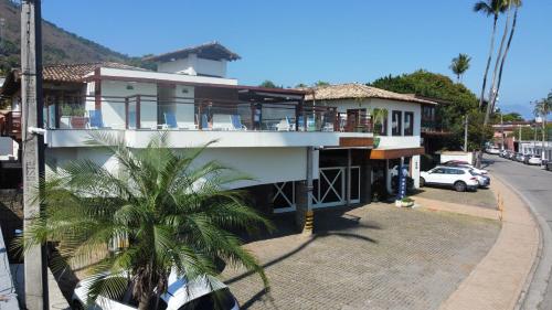 a house on the side of a street with a palm tree at Hotel Fita Azul in Ilhabela