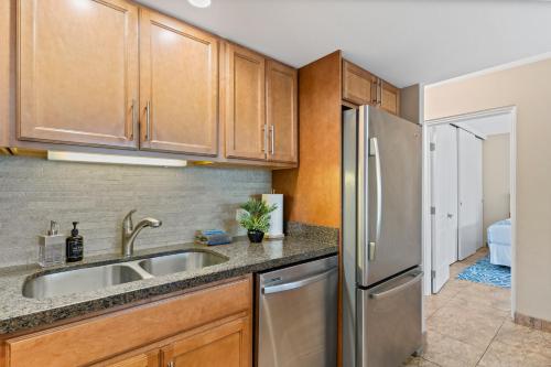 a kitchen with wooden cabinets and a stainless steel refrigerator at Perfect Getaway 2BD Condo, Steps to Beach & Shops in Wailea