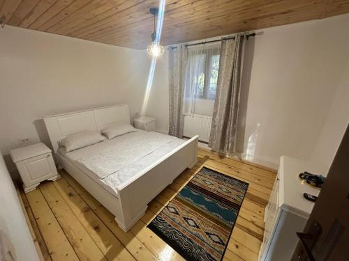 a bedroom with a white bed and a window at Cabana de lângă Vale in Budureasa