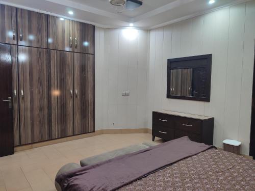 a bedroom with a bed and a dresser and a television at Fully Serviced Holiday Homes Near Emporium Mall & Expo Center in Lahore