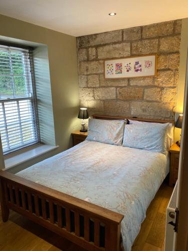 a bedroom with a bed and a brick wall at Everley Cottage in Scarborough