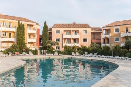 une piscine avec des chaises et des bâtiments en arrière-plan dans l'établissement Les Issambres Lauriers - maeva Home - Appartement 2 pièces 4 personnes - Prestige MAE-8981, aux Issambres