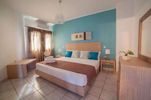 a bedroom with a large bed and a blue wall at Minos Apartments & Studios in Sitia