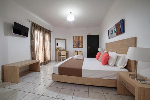 a bedroom with a bed and a desk and a television at Minos Apartments & Studios in Sitia