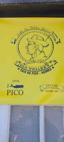 a yellow sign on a window of a pizza at Casas do Baleeiro - Casa da Vinha in Cais do Pico