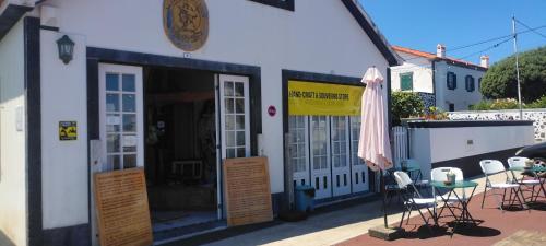 a building with a patio with chairs and an umbrella at Casas do Baleeiro - Casa da Vinha in Cais do Pico