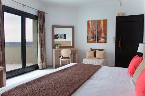 a bedroom with a bed and a desk and a window at Minos Apartments & Studios in Sitia