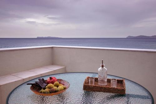 a glass table with a bowl of fruit on a balcony at Minos Apartments & Studios in Sitia