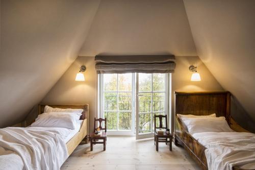 two beds in a attic room with a window at Entzückende Reetdachkate am Feldrand mit Kamin in Nieby