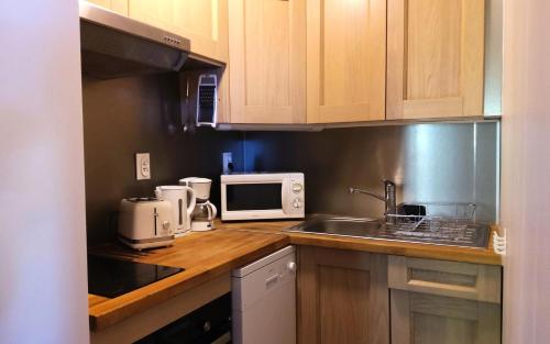 une cuisine avec un évier et un micro-ondes dans l'établissement Résidence Deux Tetes - Très agréable 2 pièces dans un quartier calme à 50 mètres des pistes MAE-4491, à Arc 1600