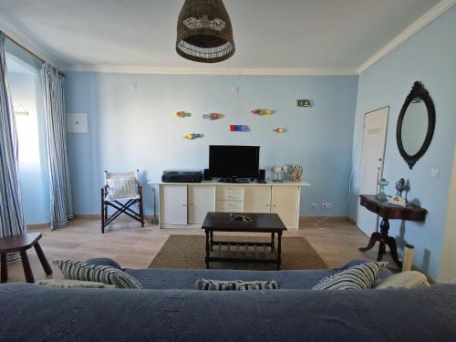 a living room with a couch and a tv at Casa do Terraço by Madrabica in Atouguia da Baleia