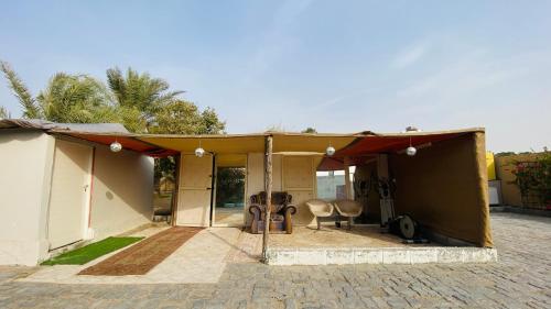 a house with a tent and a table and chairs at private farmhouse Tent Room in Al Rahba