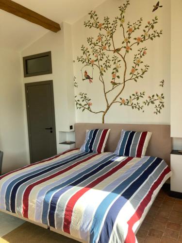 a bedroom with a bed with a tree mural on the wall at La Haute Combe in Liré