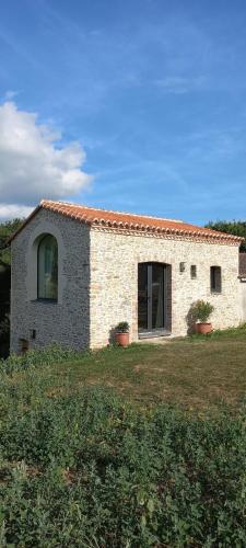 a stone house with two plants in a field at La Haute Combe in Liré