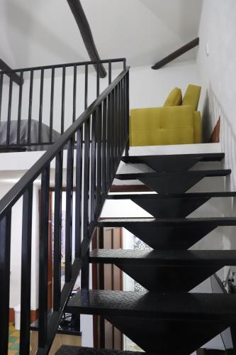 a black staircase with a yellow chair in a room at Hotel Ambar La Morada in Buga