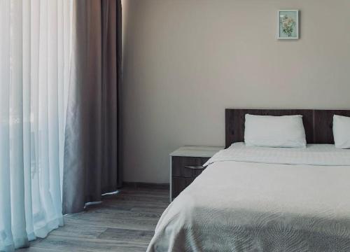 a bedroom with a bed with white walls and curtains at Green Line in Mtsvane Kontskhi