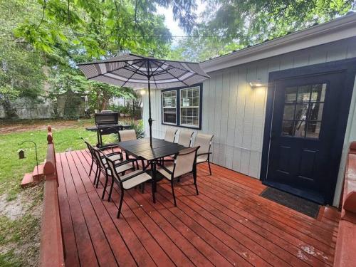 a wooden deck with a table and chairs and an umbrella at Midtown Marvel Reinvented with Contemporary Charm in Gainesville