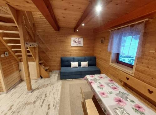 a bedroom with a blue couch in a wooden room at Chatka Alexandra in Litmanová
