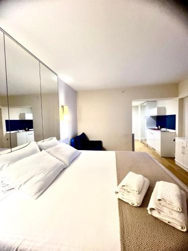 - une chambre avec un grand lit blanc et des miroirs dans l'établissement Orbi city apartment, à Batoumi