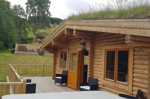 a log cabin with a porch with a grass roof at Orchid lodge in Bridge of Tilt