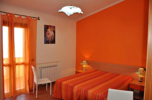 a bedroom with orange walls and a bed and a window at Villa Bella Vista in Capo Vaticano