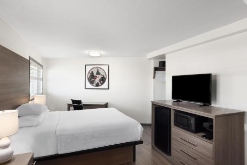 a bedroom with a bed and a flat screen tv at Ramada by Wyndham Medford Airport North in Medford