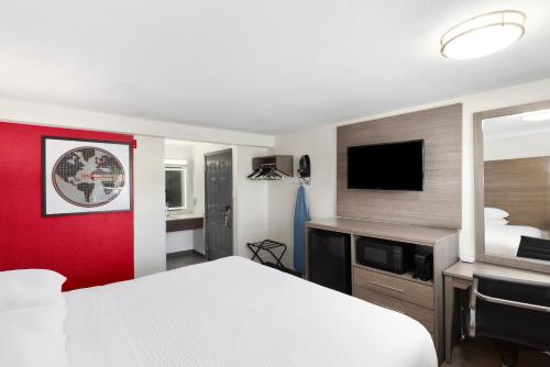 a hotel room with a bed and a flat screen tv at Ramada by Wyndham Medford Airport North in Medford