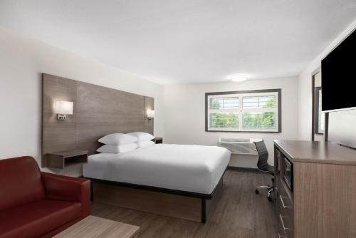 a hotel room with a bed and a red chair at Ramada by Wyndham Medford Airport North in Medford