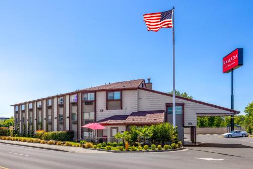 a hotel with an american flag in front of it at Ramada by Wyndham Medford Airport North in Medford