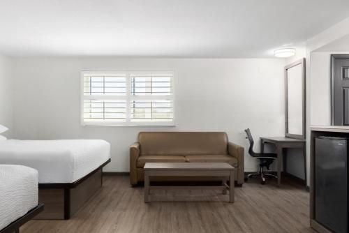 a room with a bed and a couch and a desk at Ramada by Wyndham Medford Airport North in Medford