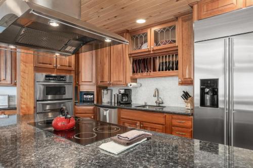a kitchen with wooden cabinets and a stainless steel refrigerator at Ski In, Ski Out, Steam Shower in Unit, Outdoor Hot Tub in Steamboat Springs