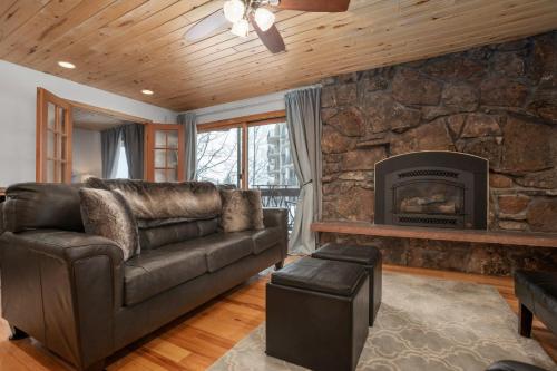 a living room with a leather couch and a stone fireplace at Ski In, Ski Out, Steam Shower in Unit, Outdoor Hot Tub in Steamboat Springs