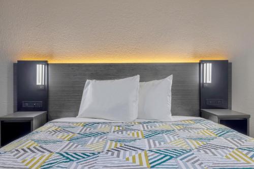 a bed with white pillows and two night stands at Studio 6 Little Rock AR South in Little Rock