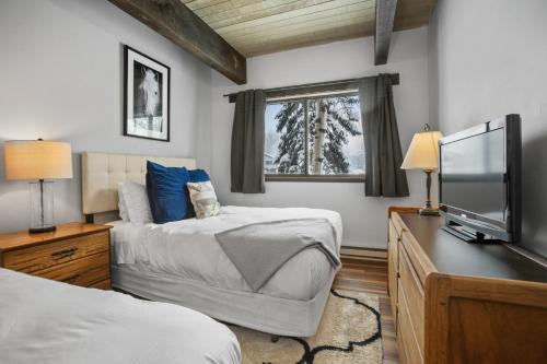 a bedroom with two beds and a flat screen tv at Heated Pool, Private Washer & Dryer, Ski In, Ski Out, Just Remodeled in Steamboat Springs