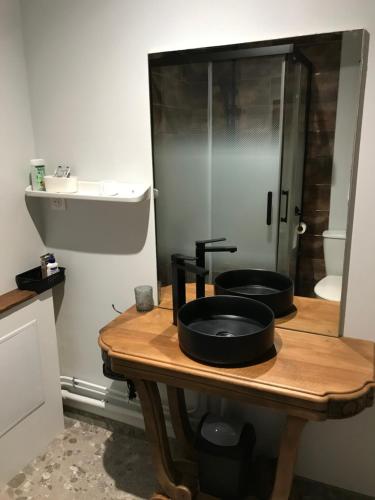 a bathroom with two black sinks on a wooden table at Gîte Charmant La Combette in Thouron