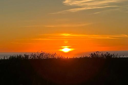 a sunset on the beach with the sun in the sky at Oceanview Oasis in Copalis Beach