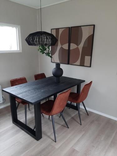 a black dining room table with chairs and a lamp at Boshuisje Het Groene Hert 113 in Haarle