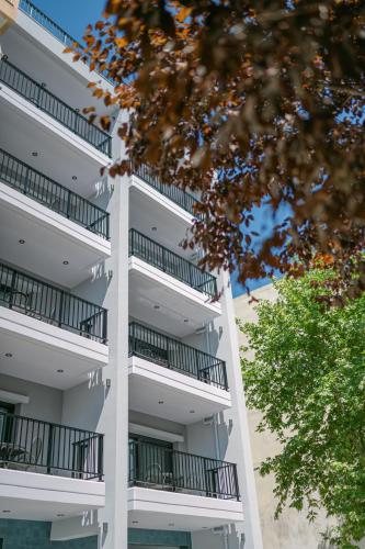 an apartment building with balconies and a tree at Oktolia suites in Alexandroupoli