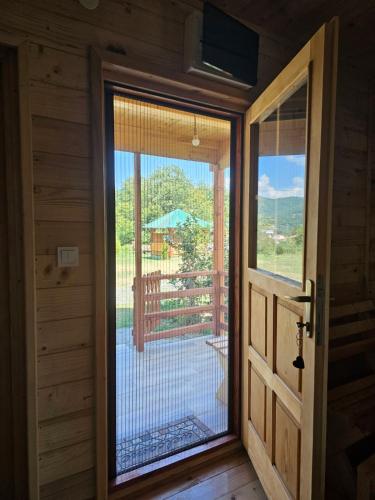a door to a room with a view of a balcony at Konaci Očeva Zemlja Vikendica i Bungalovi in Mojkovac
