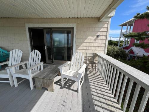 two white chairs and a bench on a porch at No Regrets in Emerald Isle