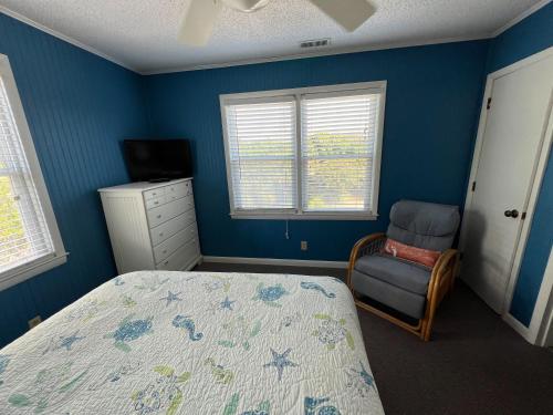 a bedroom with blue walls and a bed and a chair at No Regrets in Emerald Isle