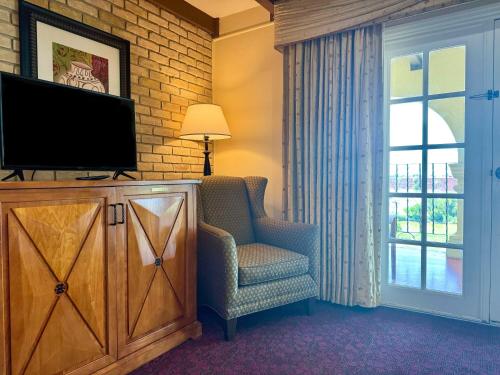 a living room with a tv and a chair and a window at La Posada Hotel in Laredo