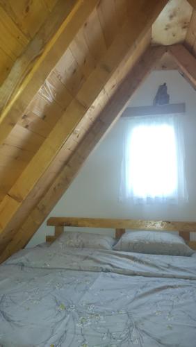 a bed in a attic with a window at Vikendica Gradačka Poljana in Šavnik