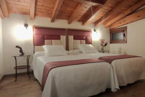 two large beds in a room with wooden ceilings at Vivienda Rural Perotxenea Landetxea in Doneztebe