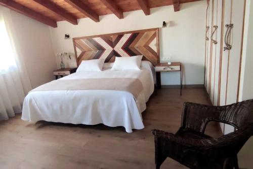 a bedroom with a large white bed and a chair at Vivienda Rural Perotxenea Landetxea in Doneztebe