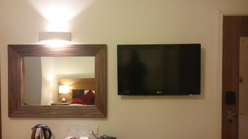 a flat screen tv on a wall next to a mirror at Gateway Express in Newport